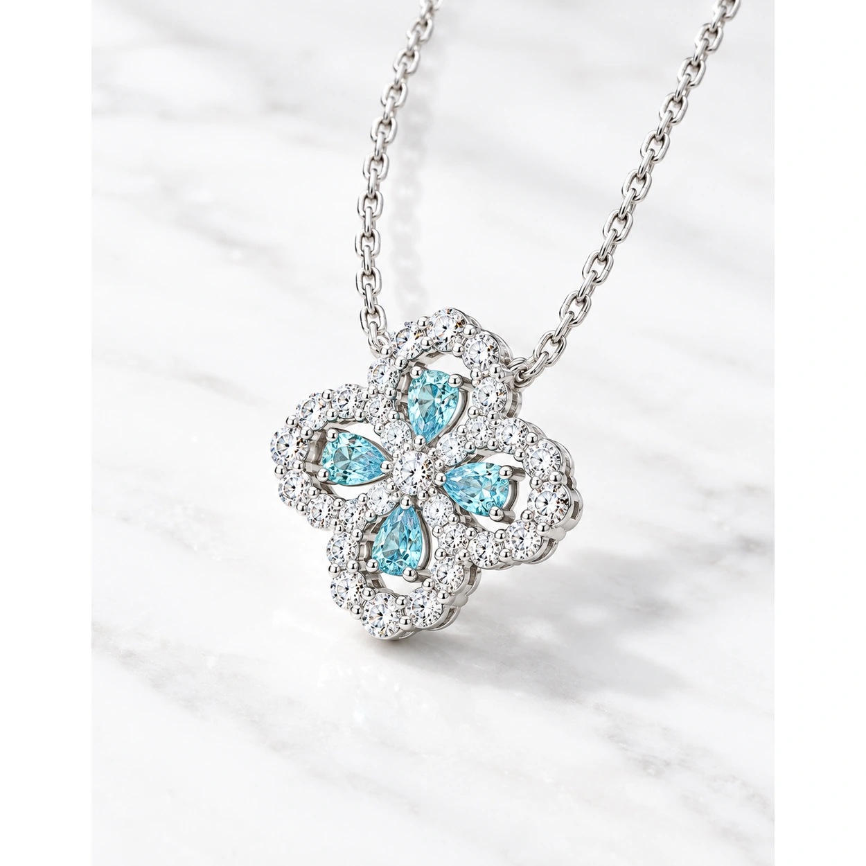 Angled view of the Ocean Luck clover pendant showing blue teardrop stones and scalloped borders