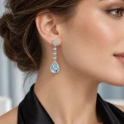 Close-up of a model wearing a Sky Serenade blue topaz dangle earring with a heart-shaped top