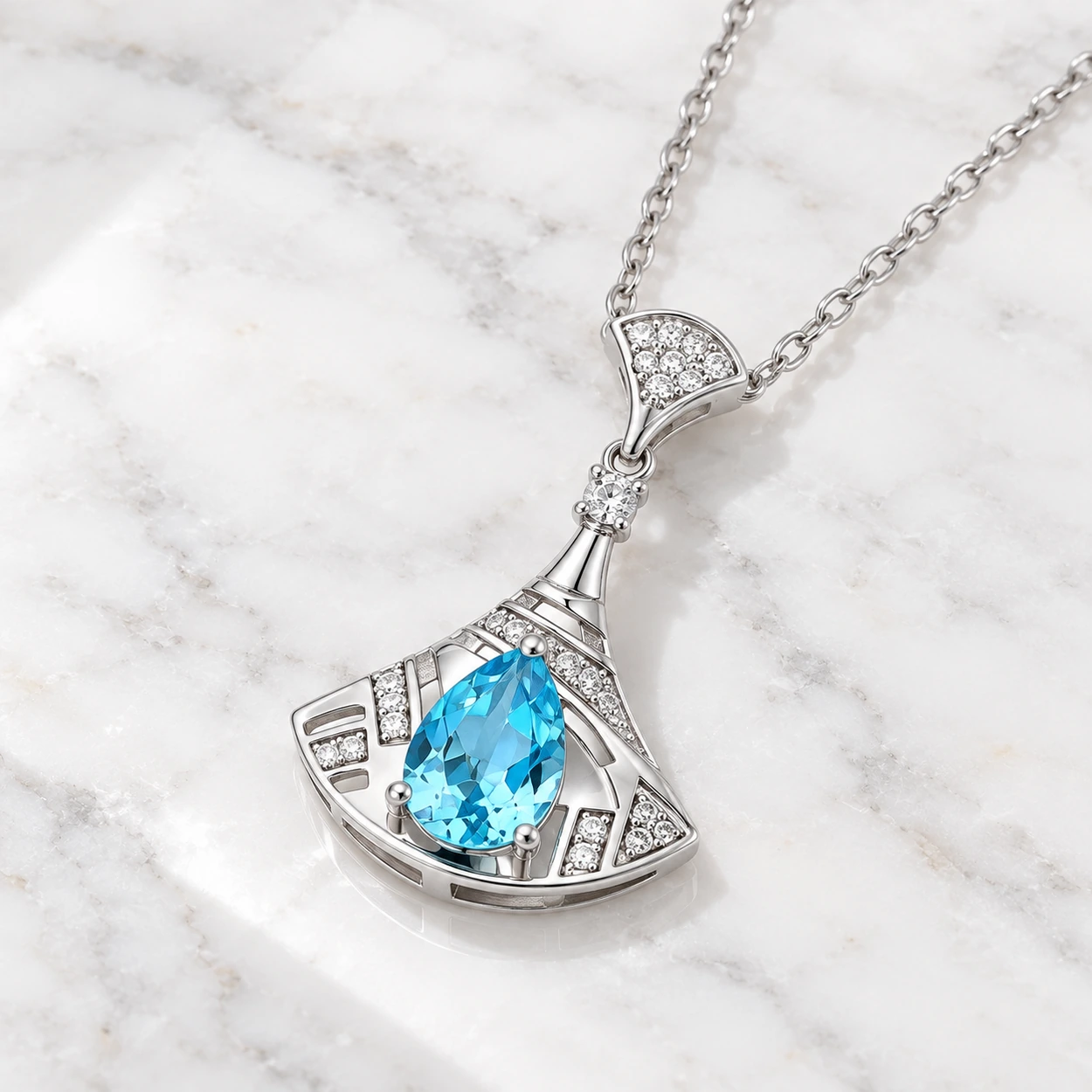 45-degree view of the Ocean Reverie necklace showing its blue teardrop topaz and sculptural silver fan