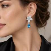 Close-up of a model wearing an Azure Blossom blue topaz teardrop earring with a sparkling floral top