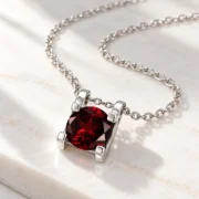 Side profile of the natural garnet pendant showing its silver setting and chain attachments