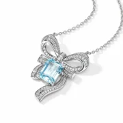 Angled view of the sculpted silver bow, open loops and emerald-cut blue topaz pendant
