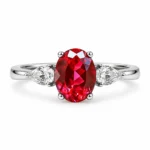 Front view of a red three stone ring with an oval center and pear-shaped side stones
