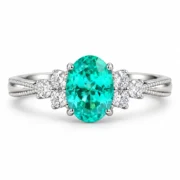 Front view of a teal cluster ring with an oval blue-green center and clear side stones
