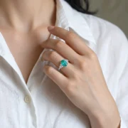 Oval blue-green cluster ring displayed on a warm brown surface